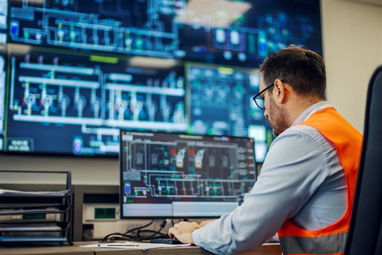 A person seating at a screen in a manufacturing facility illustrating the importance of cybersecurity in all aspects of a product lifecycle.